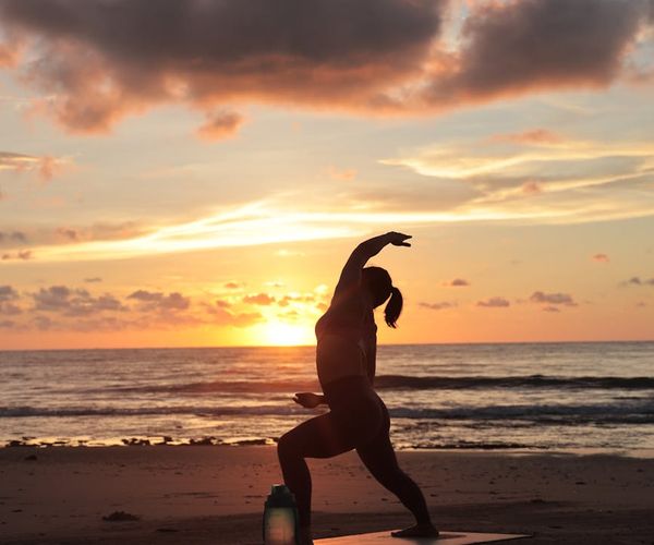 Silhouette of a person in a powerful yoga pose at sunrise.